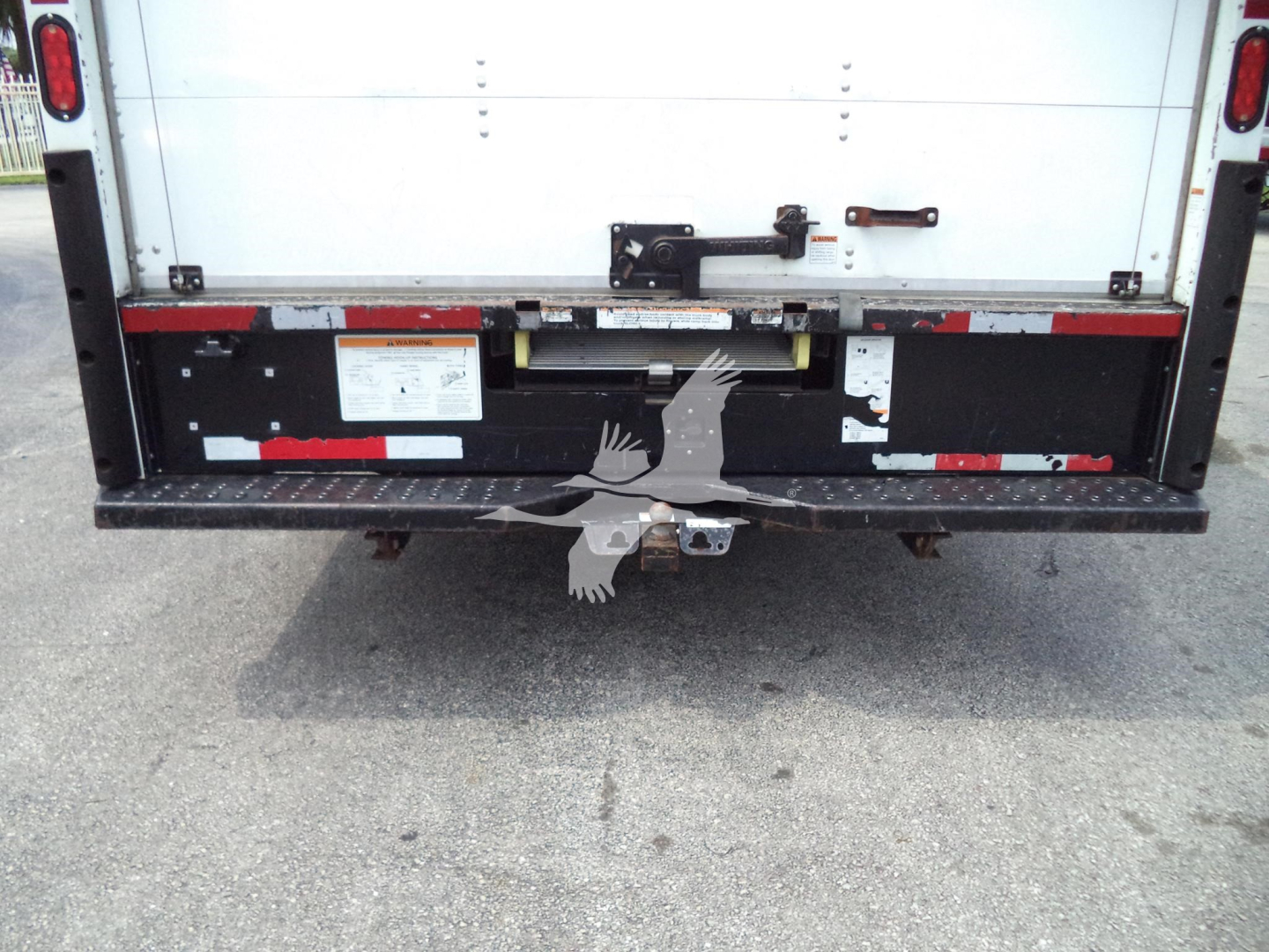 Rear view of a 2022 Ford E350 cargo van with a cutaway/high cube body showing the tailgate and rear bumper; stock stickers and latches visible.