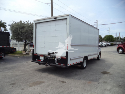 Box truck rear and side view showing cargo box with rear doors, bumper, and wheel; no legible text visible on labels from this angle.