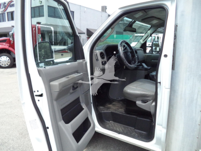 Ford E-350 cargo van interior view with open driver door showing steering wheel, dashboard, and front seat.