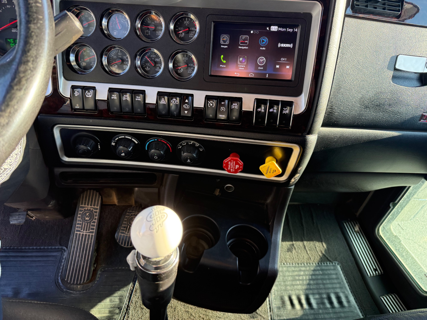 Kenworth W900L truck interior dashboard with multiple gauges, touchscreen display, control switches, and gear shifter.