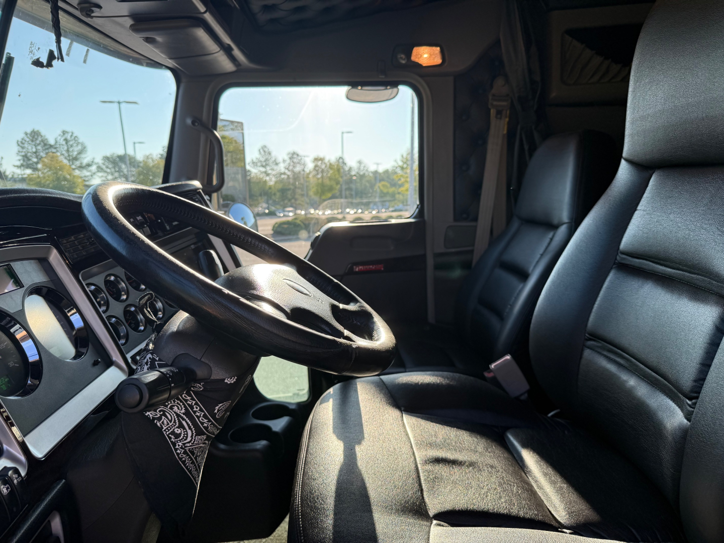 Cab interior of a 2022 Kenworth W900L with black steering wheel, dashboard gauges, and driver seat visible.