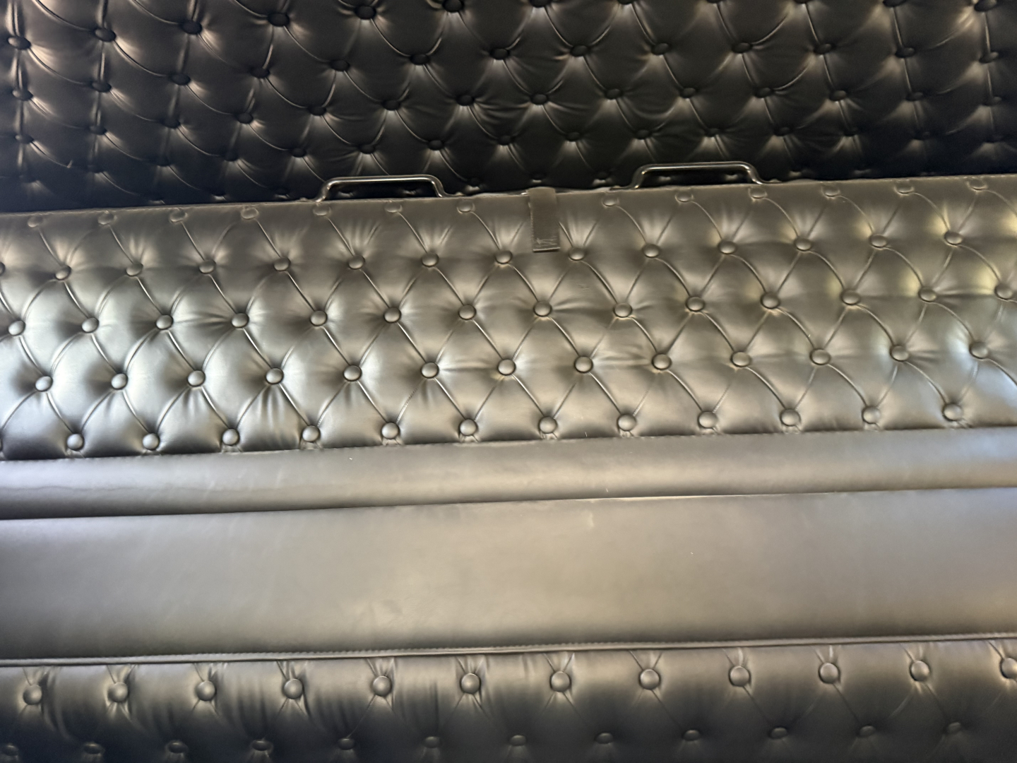 Kenworth W900L interior cargo area with tufted black leather upholstery and metal handles visible along top edge.