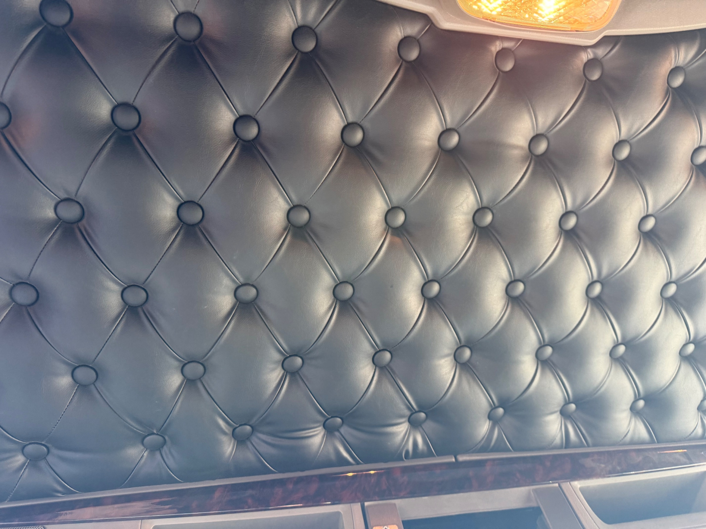 Close-up of a black diamond-stitched upholstery panel in a Kenworth truck interior with a small light at the top corner.