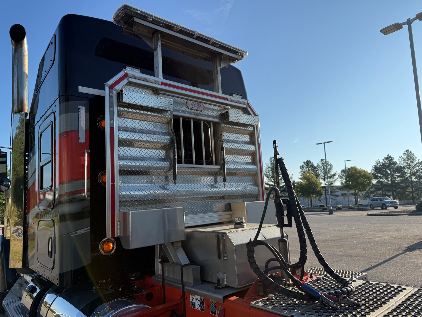 Kenworth W900L rear view showing chrome utility box, tall exhaust stack, and hitch with braided cables