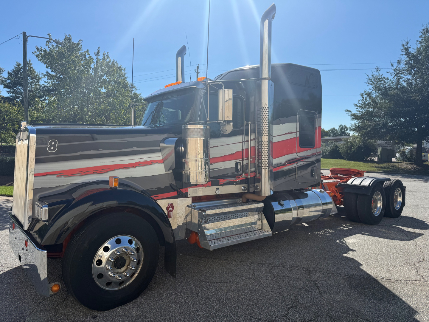 Kenworth W900L tractor-trailer truck side view showing chrome fuel tanks and exhaust stacks.