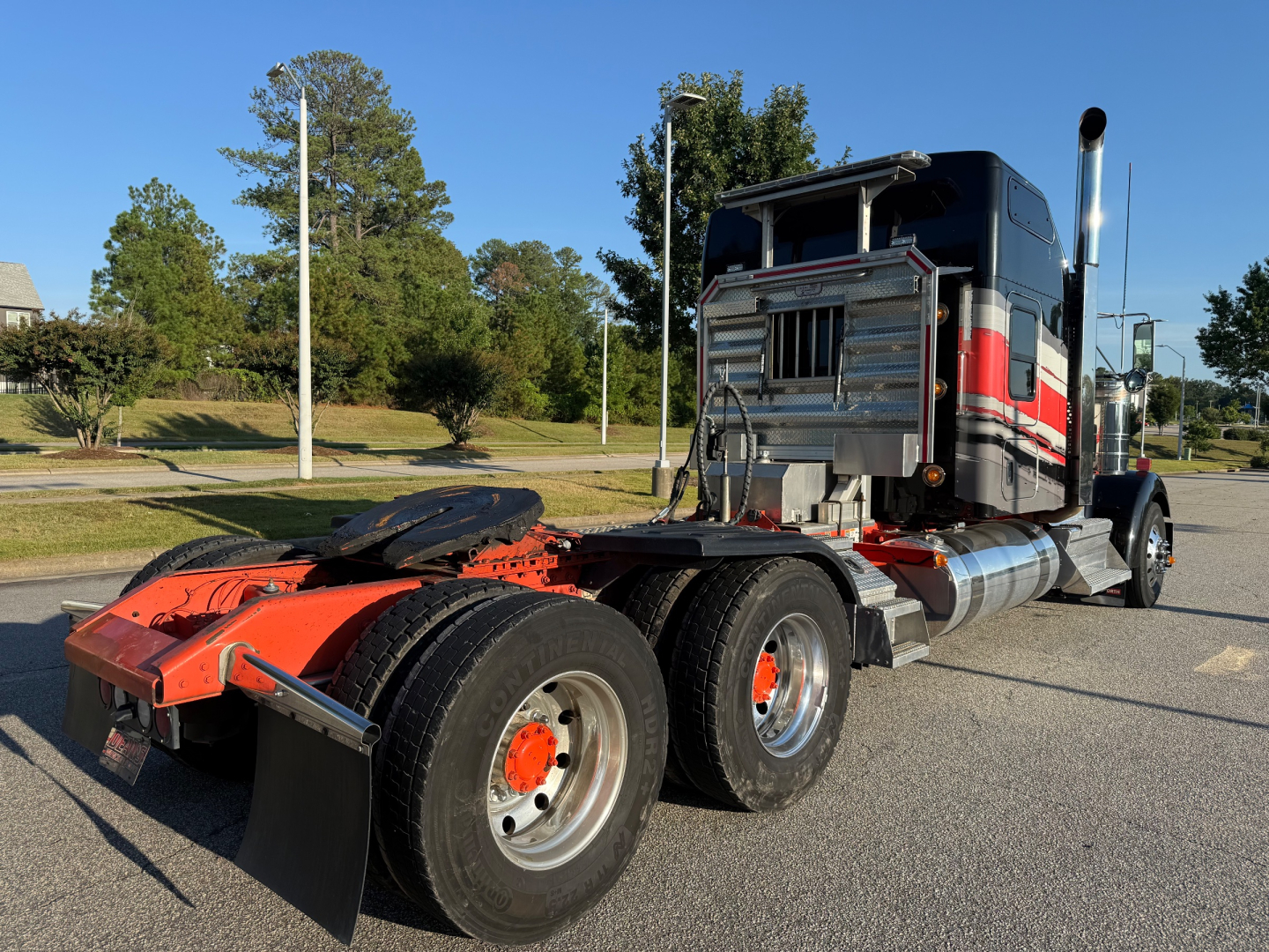 Kenworth W900L tractor chassis and cab side showing rear wheels and exhaust stack.
