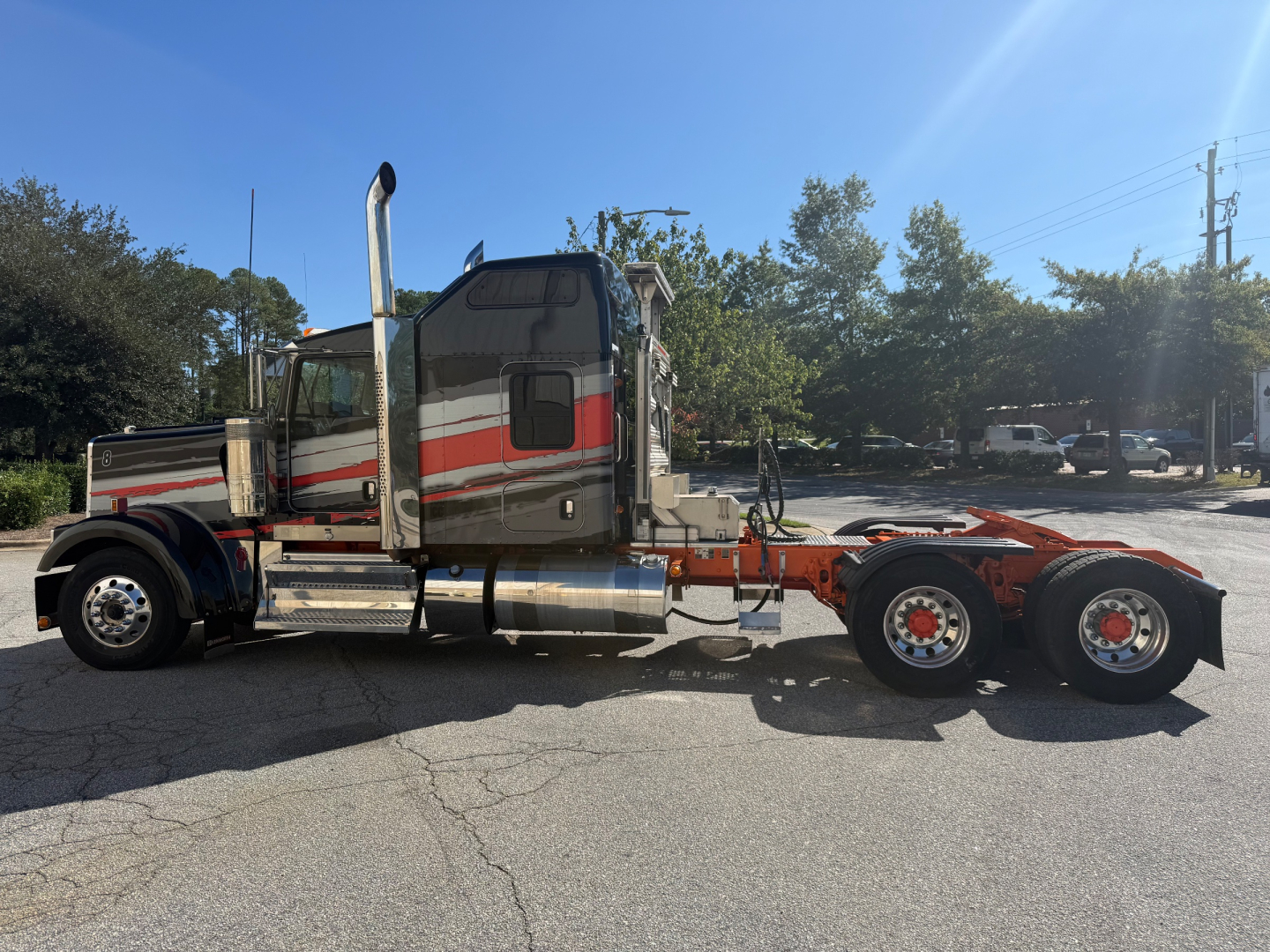 Kenworth W900L 2022 conventional sleeper tractor in profile showing dual rear axles, chrome exhaust stacks, and diamond plate steps.