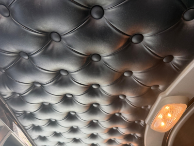 Kenworth W900L cab interior ceiling with tufted black leather and a small orange indicator light visible in the corner.