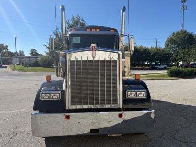 Kenworth W900L truck front view showing large chrome grille, dual tall exhaust stacks, rectangular headlights, and chrome bumper.