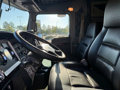 Cab interior of a 2022 Kenworth W900L with black steering wheel, dashboard gauges, and driver seat visible.