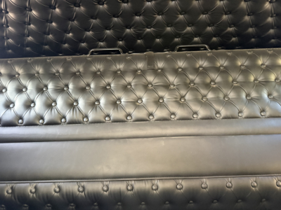 Kenworth W900L interior cargo area with tufted black leather upholstery and metal handles visible along top edge.