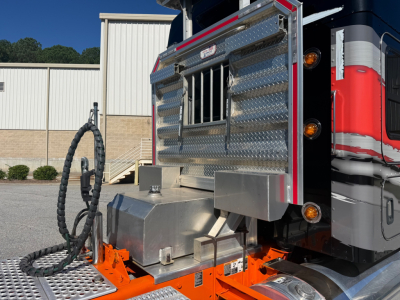 Kenworth W900L truck side showing diamond plate toolbox and fuel tank with hoses and chrome steps.