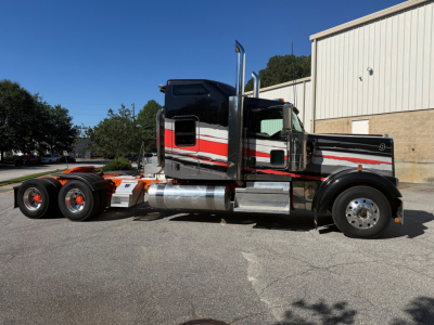 Kenworth W900L heavy-duty truck in side profile view showing sleeper cab, chrome exhaust stacks, black and red-white color scheme, 6x4 tractor configuration, aluminum fuel tanks, and tandem rear axles.