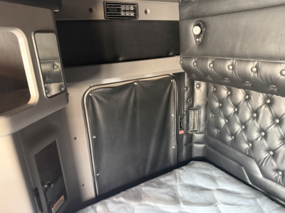 Kenworth W900L sleeper cab interior with tufted leather bed area and storage cabinet.