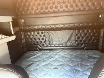 Kenworth W900L sleeper cab interior with tufted black leather seating and quilted bed cover.