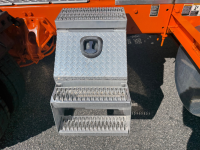 Kenworth W900L side view with aluminum diamond-plate steps and fuel access panel showing a textured metal surface.