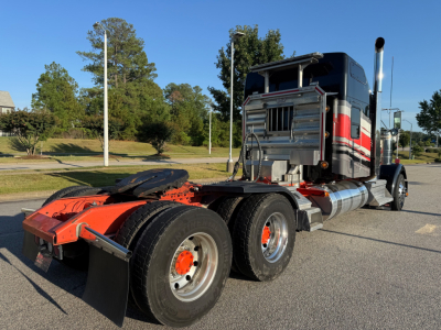 Kenworth W900L tractor chassis and cab side showing rear wheels and exhaust stack.