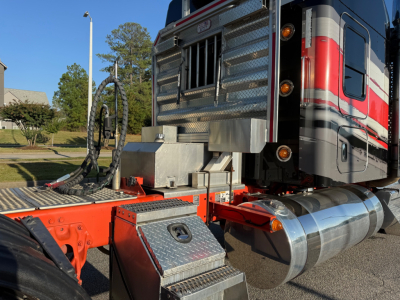 Kenworth W900L truck cab and chrome fuel tanks with metallic diamond-plate steps and red chassis.