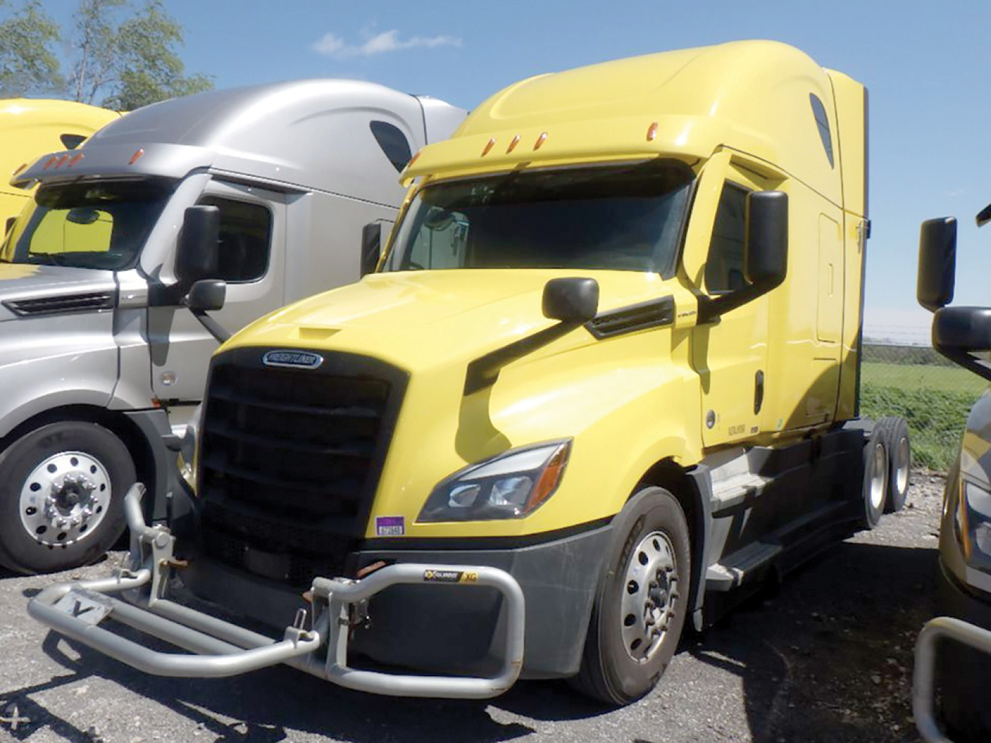 Front view of a yellow Freightliner Cascadia126 sleeper truck showing grille, bumper guard, and side mirrors.