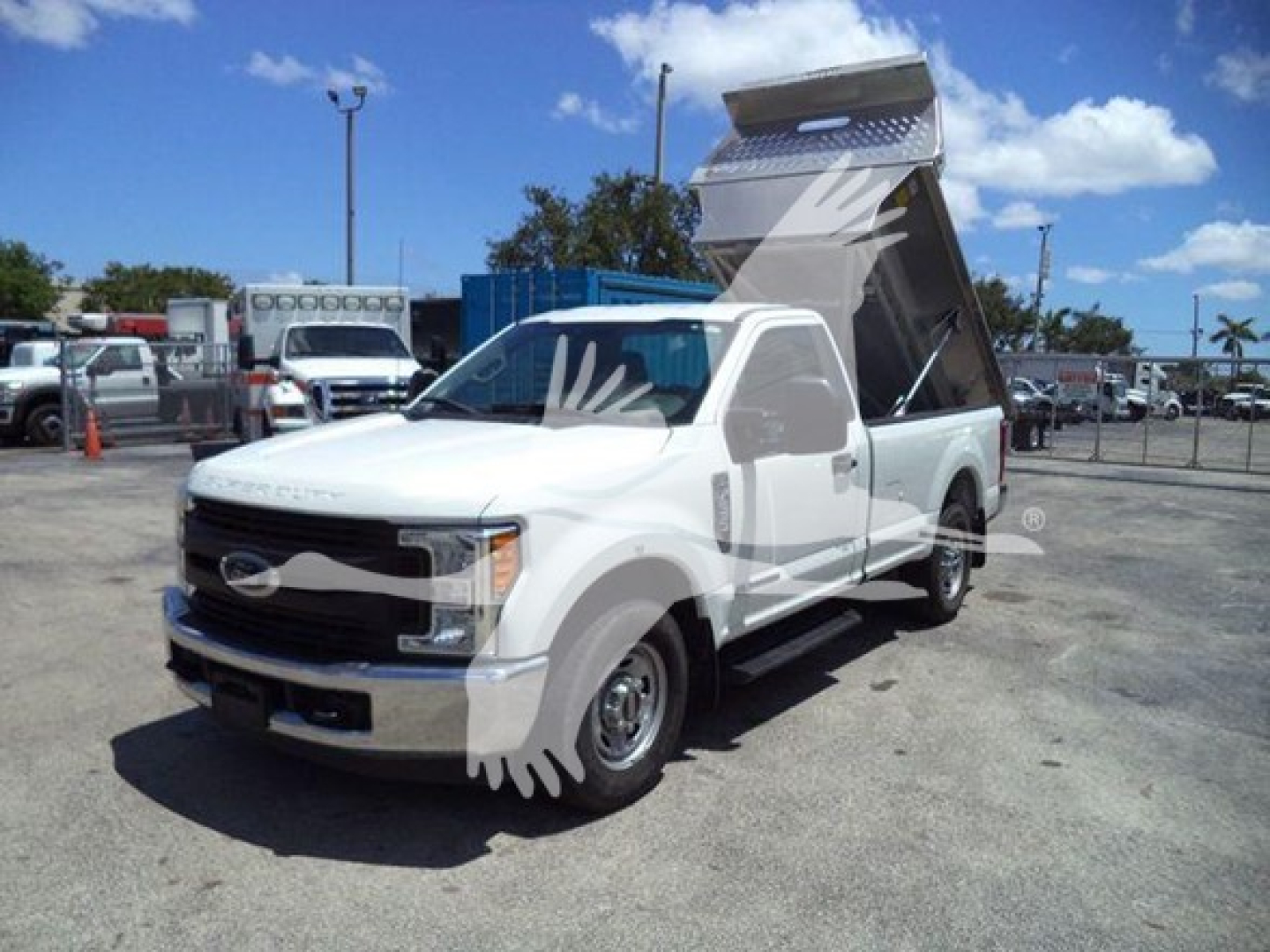Ford F-250 dump truck with raised bed in a dealership lot showing front grille and side view