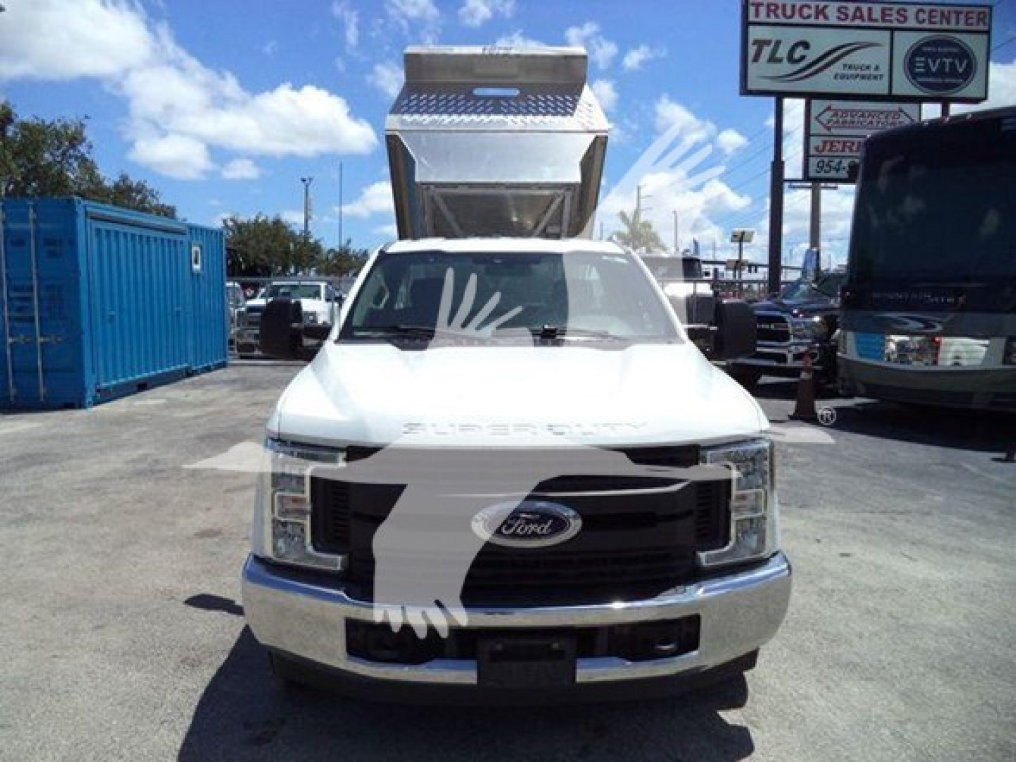 Ford F-250 front view with dump bed raised in truck lot showing Ford emblem and grille