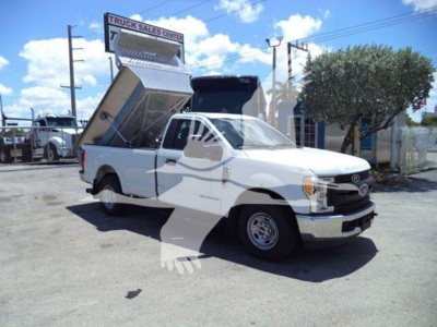 Ford F-250 dump bed truck in service bay showing raised dump bed and front grille with Ford emblem.