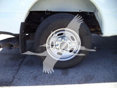 Ford F-250 wheel and front fender showing steel wheel and tire, partial wheel well, vehicle white paint.