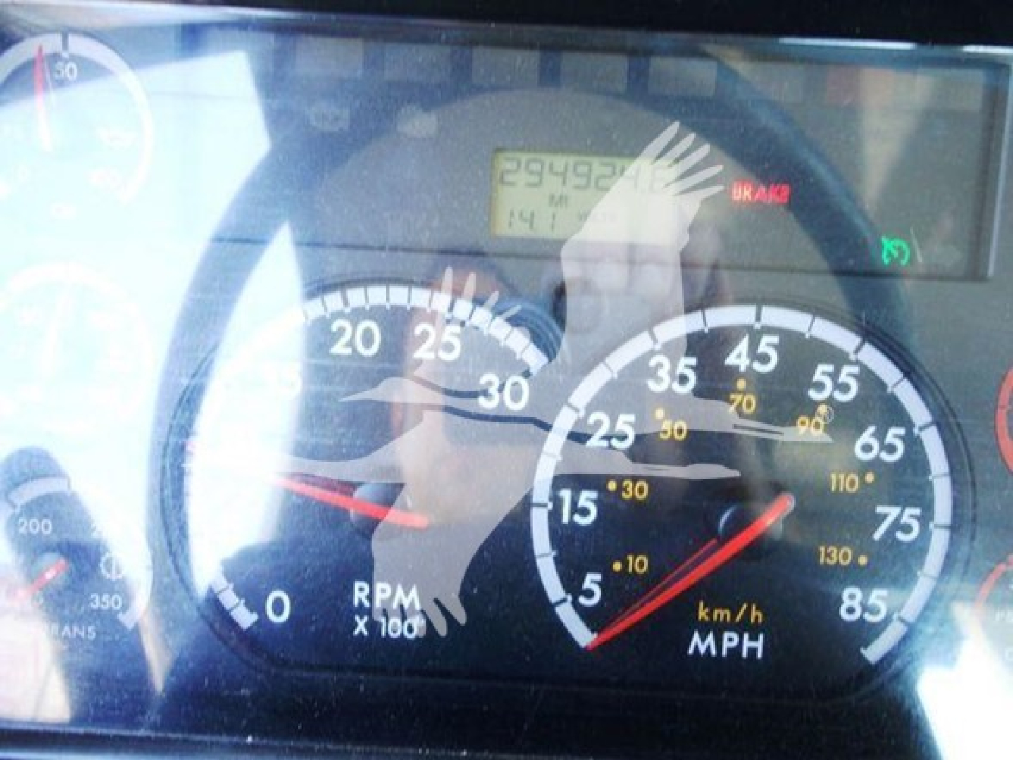 Vehicle dashboard showing speedometer and RPM gauge from a Freightliner Business Class M2 106; digital readout displays mileage and brake indicator visible.