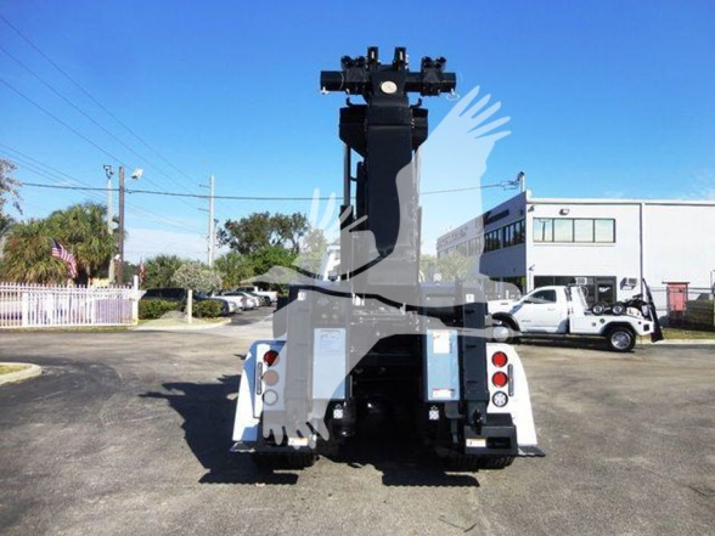 Freightliner Business Class M2 106 heavy-duty wrecker rear view showing winch and lift apparatus, dual taillights, white body, blue sky.