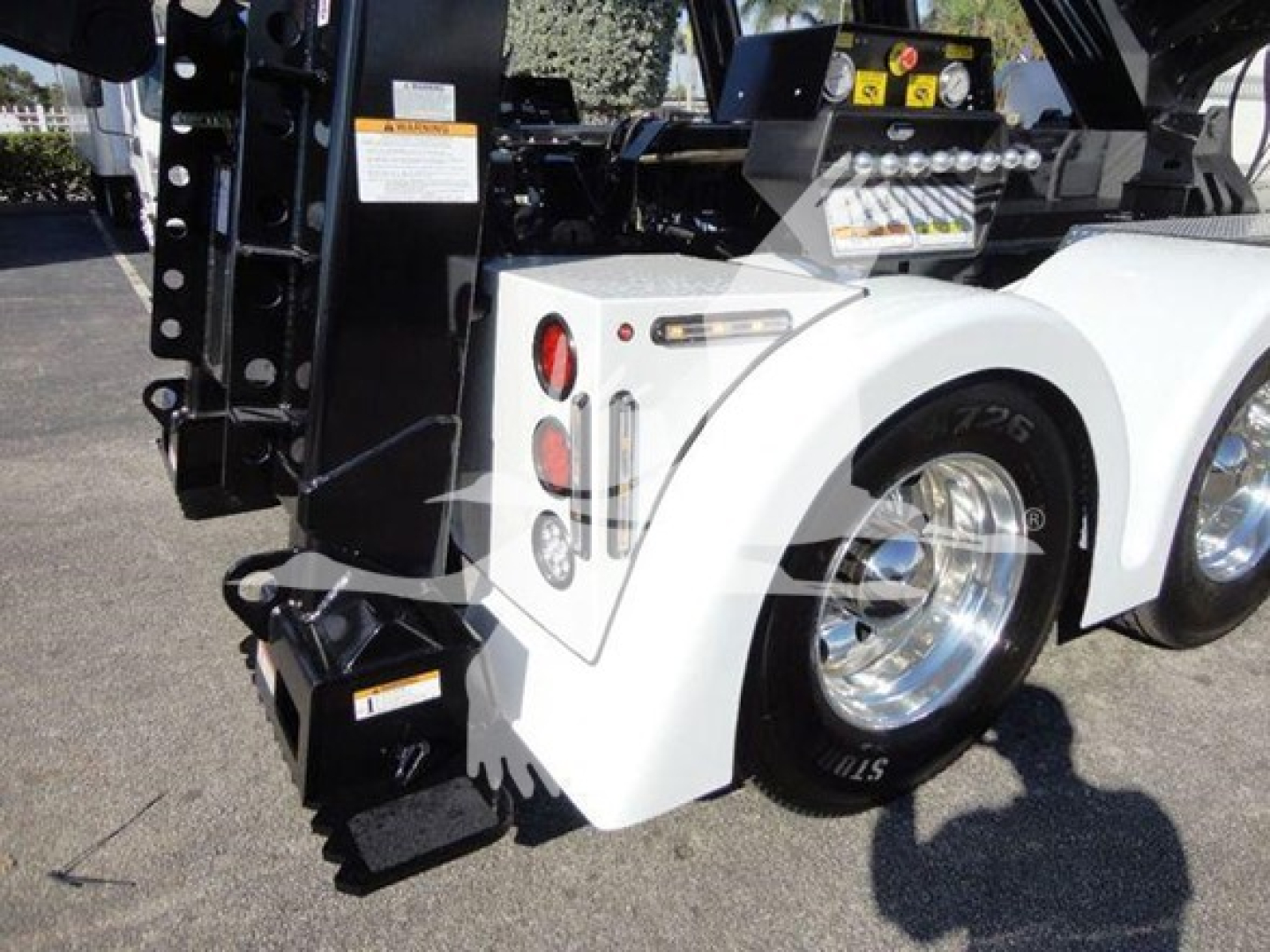 Freightliner Business Class M2 106 rear wheel and white fender, winch equipment visible with bumper lights and hydraulic components.
