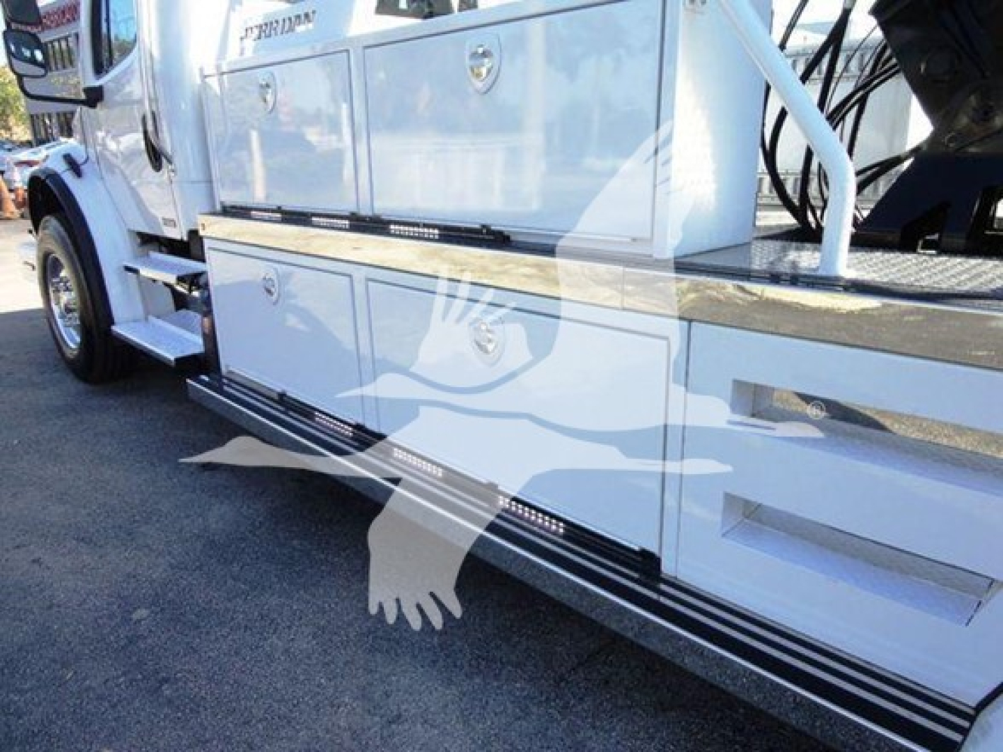 Freightliner Business Class M2 106 side view showing chrome side steps and toolbox compartments with white paint, VIN and stock number notations visible near cab.