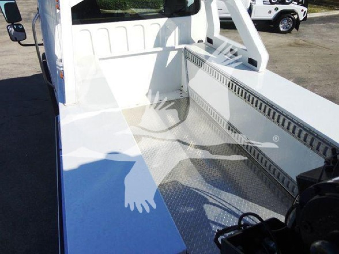 Freightliner Business Class M2 106 flatbed truck bed with winch area and diamond plate flooring, white cab visible.