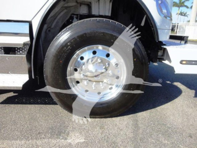 Truck front wheel and fender view showing polished aluminum wheel and black tire on Freightliner Business Class M2 106; partial cab visible.