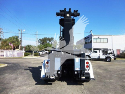 Freightliner Business Class M2 106 heavy-duty wrecker rear view showing winch and lift apparatus, dual taillights, white body, blue sky.