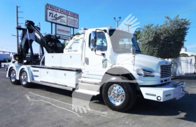 Freightliner Business Class M2 106 tow truck with flatbed and winch, side view showing white cab and equipment