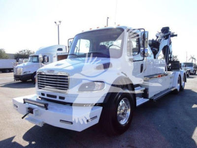 Freightliner Business Class M2 106 tow truck with mounted winch, side view showing white cab and hauler bed.