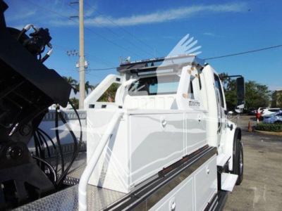 Freightliner Business Class M2 106 winch truck side view showing white body, hydraulic winch system, storage compartments, and cab; VIN label not visible.