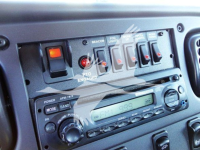 Dashboard cab controls and radio panel of Freightliner Business Class M2 106 showing switches and radio display.