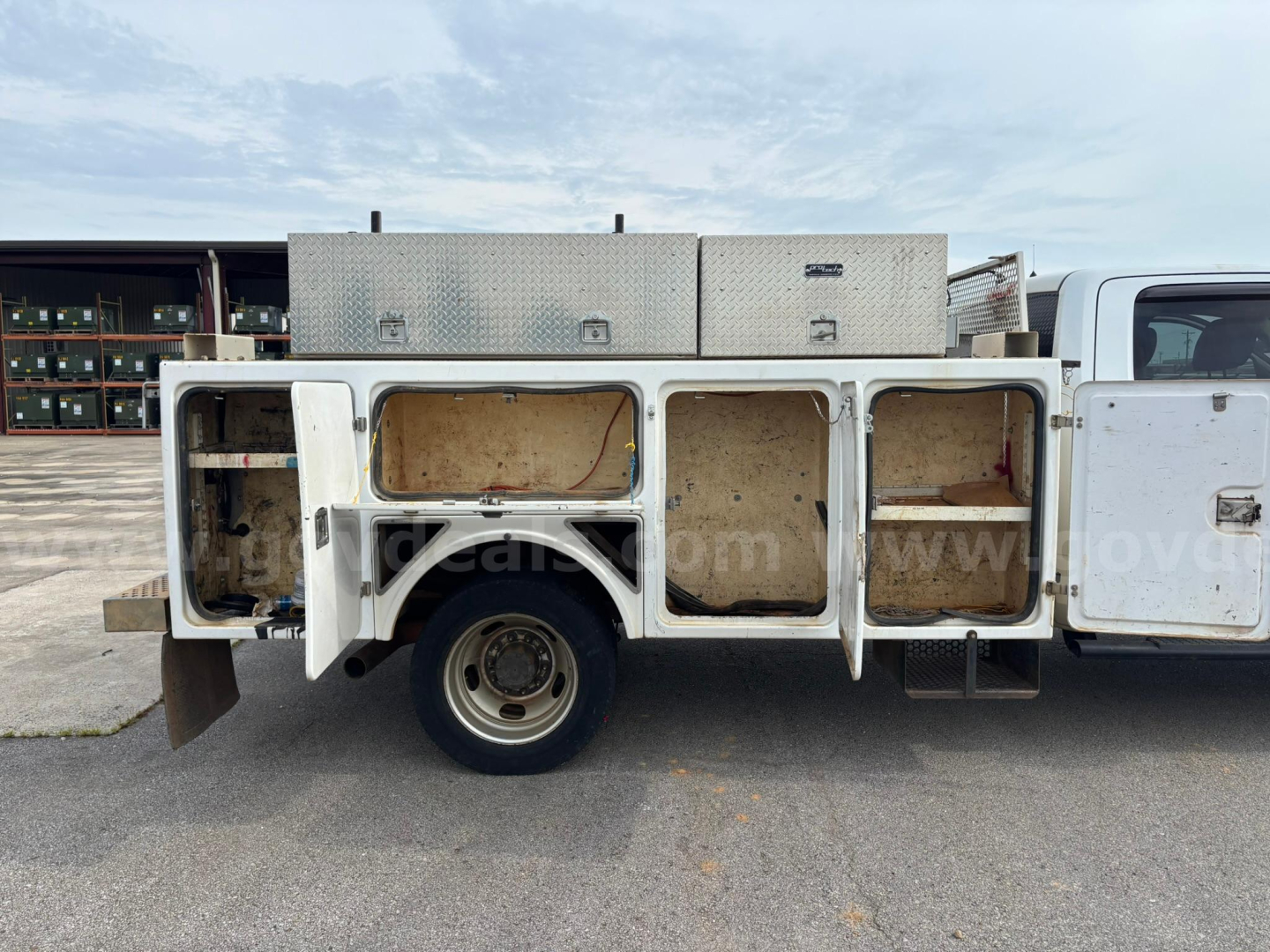 Truck bed side compartments open with storage boxes on a 2012 Dodge Ram 550 service/utility truck, side view showing aluminum toolboxes and open compartments.