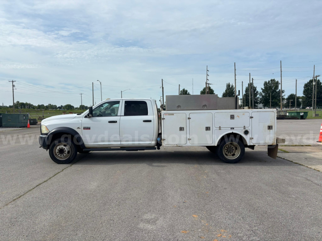 Side view of a white 2012 Dodge Ram 550 service truck with utility bed and compartments, showing stock number and VIN on vehicle in the listing photo.