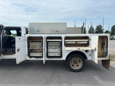 Service/utility truck side compartments open revealing multiple tool drawers and storage bays, Dodge Ram 550 with toolbox equipment in bed.