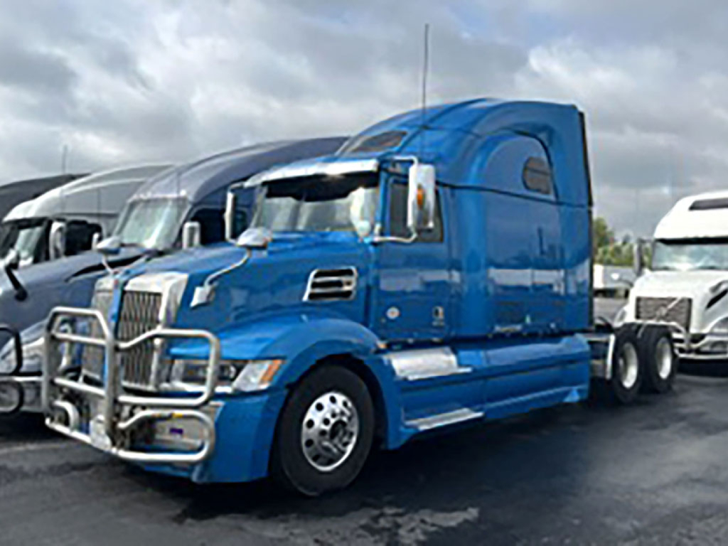 Truck in blue 2022 Western Star 5700XE conventional sleeper with chrome bumper guard and aerodynamic cab. Side view shows dual rear axles and chrome accents.