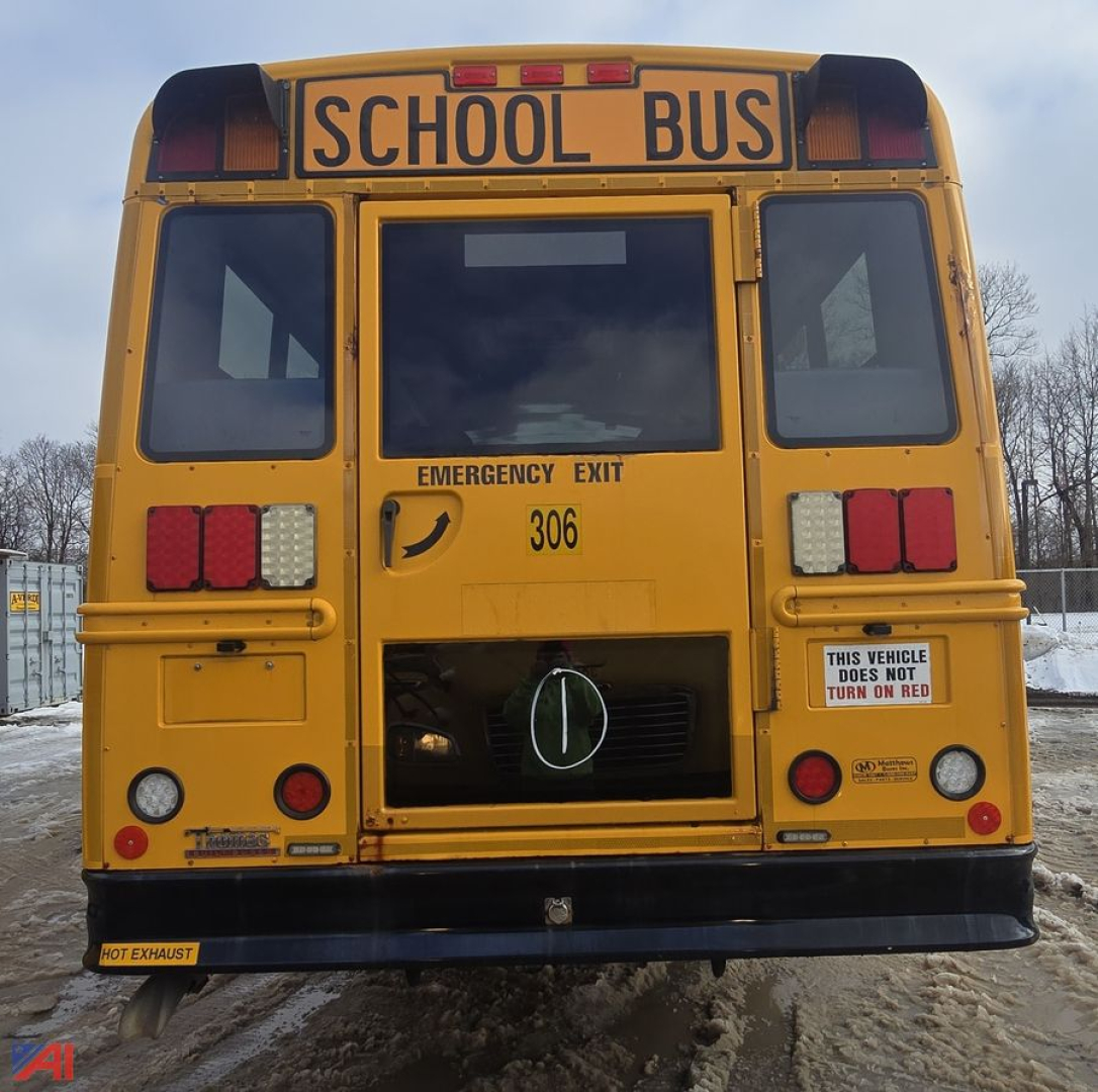 Front view of a yellow 2015 Freightliner B2B school bus with 'SCHOOL BUS' sign, emergency exit, rear lights, and a visible door area.
