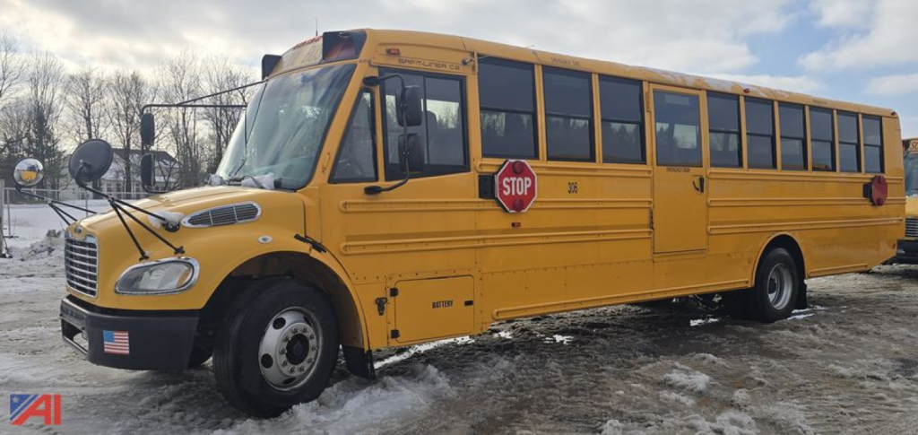 School bus side view showing yellow Freightliner B2B school bus with stop sign and doors, snow on ground.