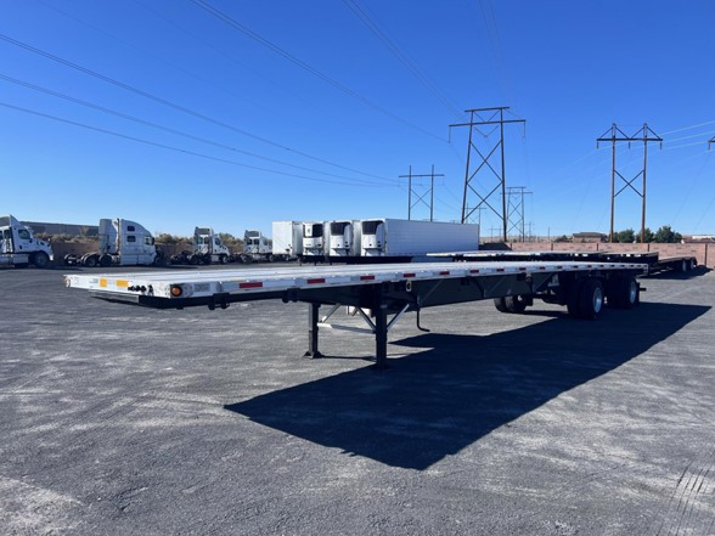 Flatbed trailer with long deck and tandem axles, Utility 4000Ae tag visible in lot of trailers.