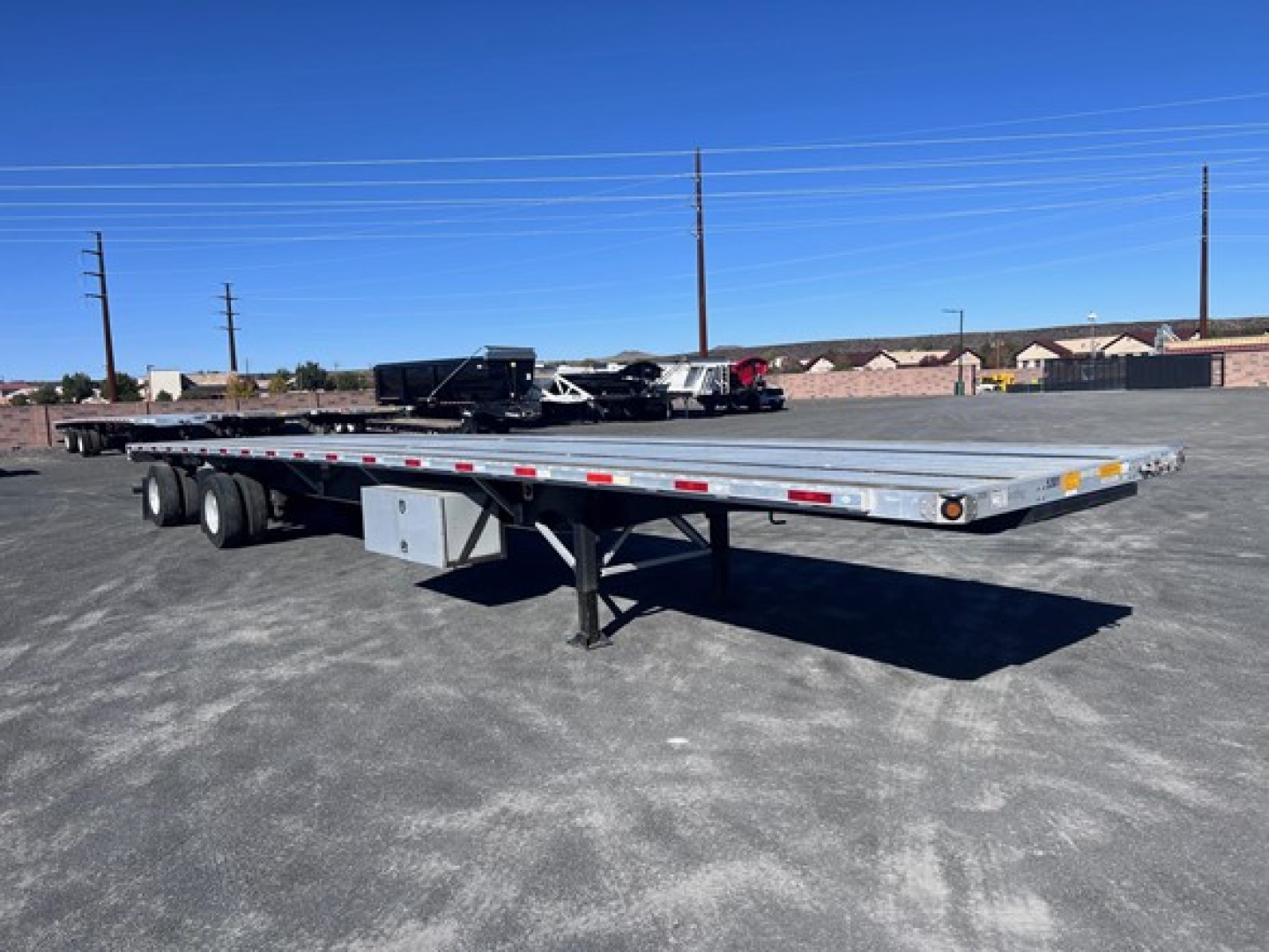 Flatbed trailer showing long steel deck with dual rear axles and a gooseneck hitch, Utility 4000AE trailer in a parking lot.