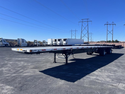 Flatbed trailer with long deck and tandem axles, Utility 4000Ae tag visible in lot of trailers.