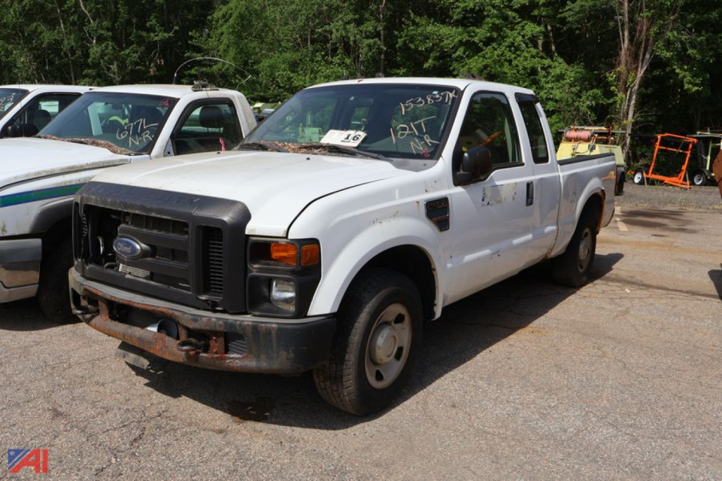 White Ford F-250 Super Duty pickup truck front-left view. Rust on bumper, black grille, single cab with long bed, standard wheels, worn headlight area.