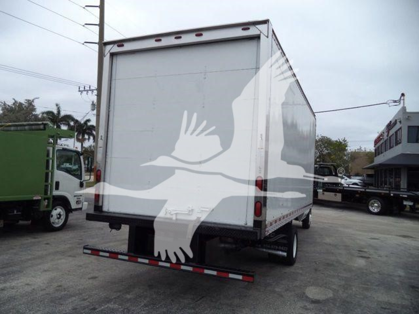 Rear view of a box truck on a lot, with white mobile box body, rear doors, and a white overhead warning light; no visible brand labels.