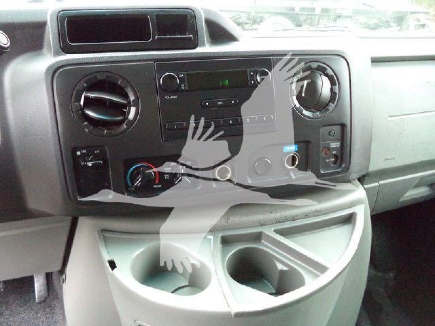 Ford E-Series van dashboard showing media controls, HVAC knobs, and cup holders.